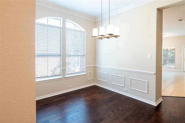 a view of an empty room with wooden floor fridge and a window