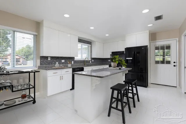 a kitchen with a refrigerator a stove a sink a dining table and chairs