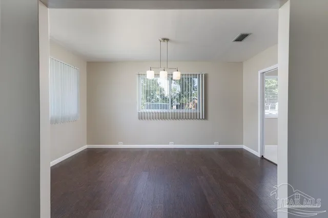 a view of an empty room with wooden floor fireplace and a window