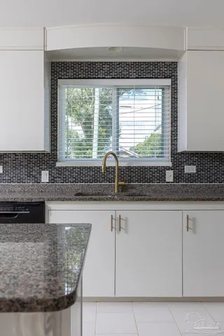 a kitchen with granite countertop a sink and a white wooden cabinets