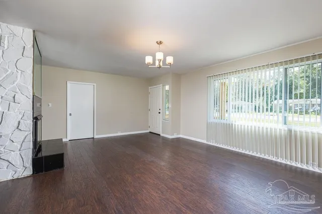 a view of an empty room with window and wooden floor