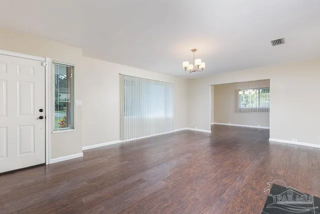 a view of an empty room with wooden floor and a fireplace