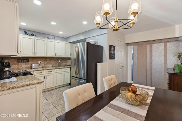 a kitchen with stainless steel appliances granite countertop a refrigerator a stove a sink dishwasher and white cabinets with wooden floor