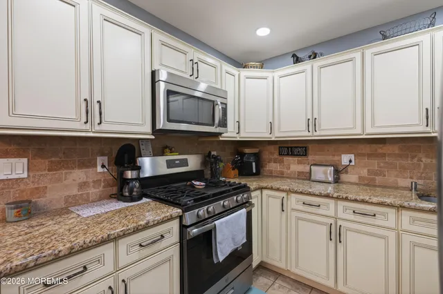 a kitchen with granite countertop white cabinets and a stove top oven