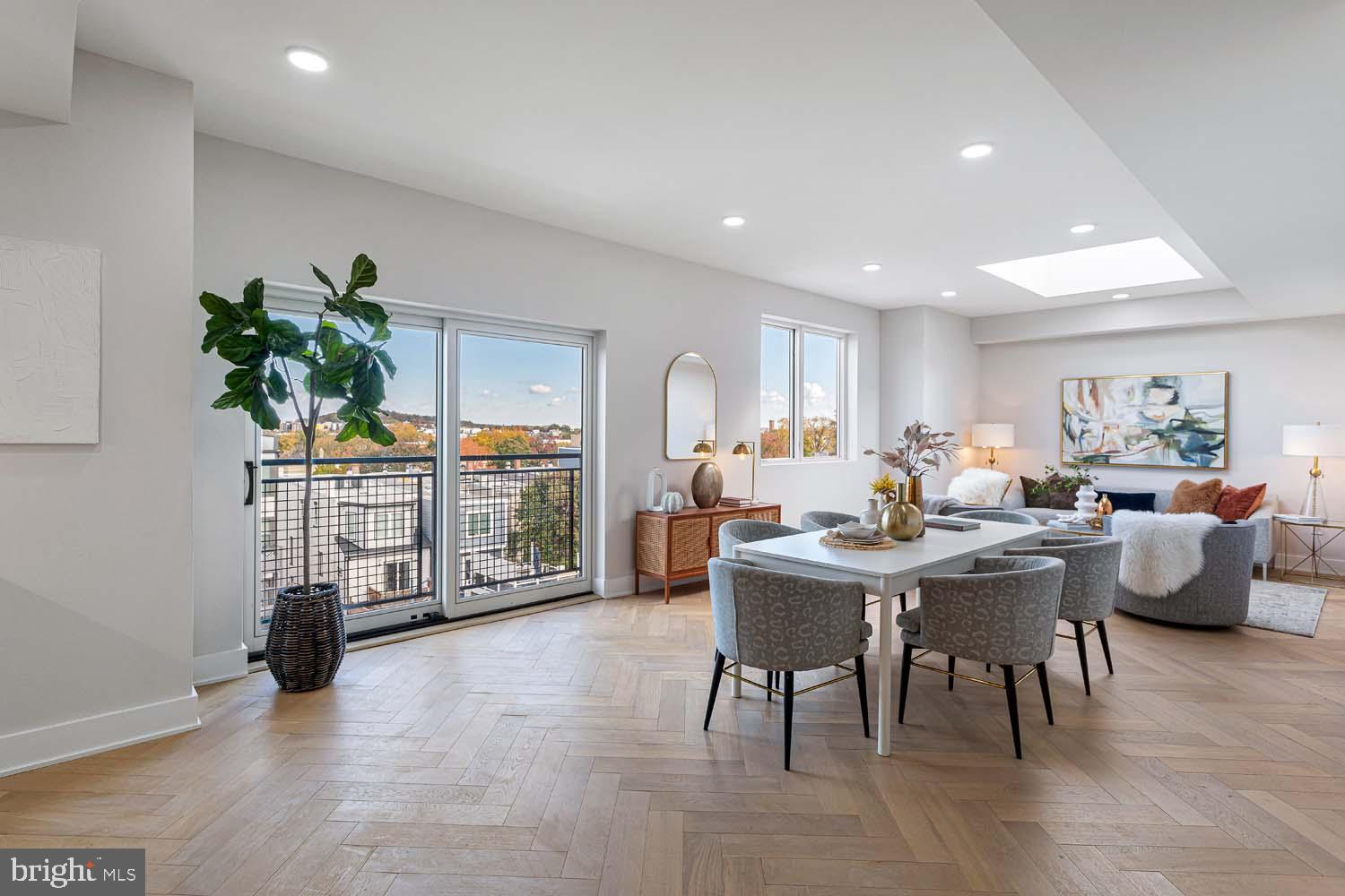 a living room with furniture a potted plant and open kitchen view