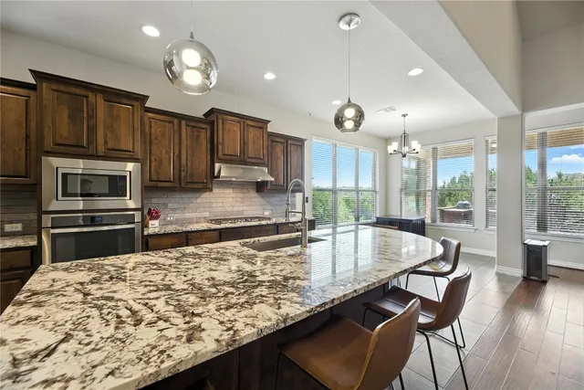 a kitchen with stainless steel appliances granite countertop a stove a sink a microwave and wooden cabinets