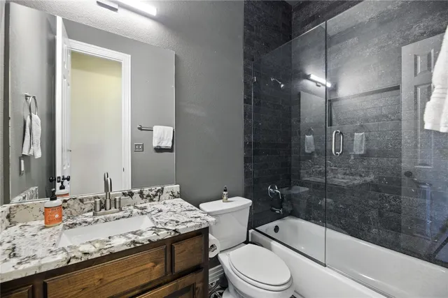 a bathroom with a granite countertop sink a toilet and shower
