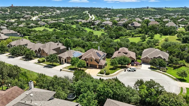 an aerial view of residential houses with outdoor space and trees all around