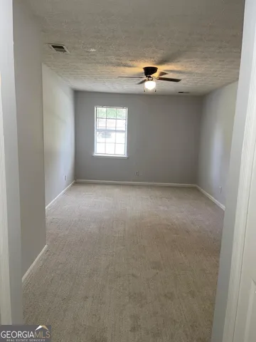 an empty room with windows and chandelier fan