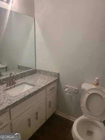 a bathroom with a granite countertop toilet and a sink