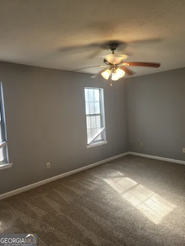 a view of a big room with windows and chandelier fan
