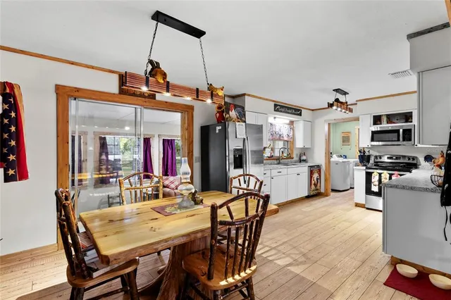 a view of a dining room and livingroom with furniture wooden floor a rug a painting and a chandelier