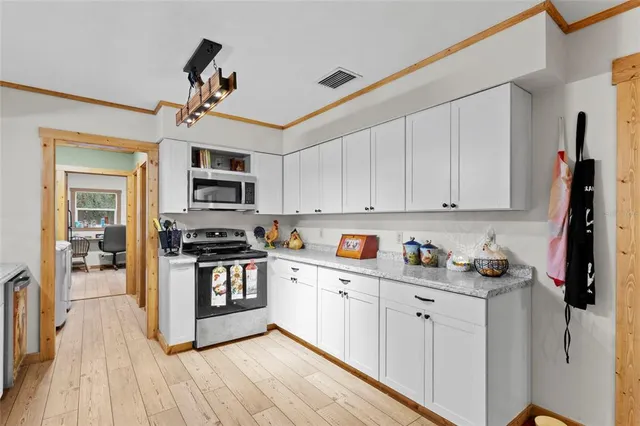 a kitchen with stainless steel appliances granite countertop a stove and white cabinets