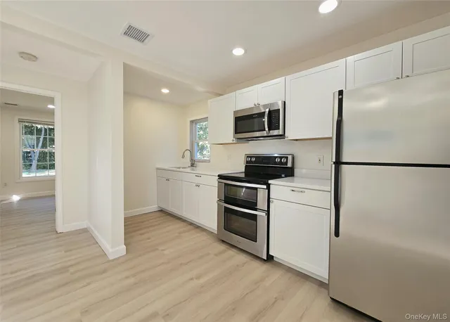 a kitchen with a refrigerator a stove top oven and wooden floor