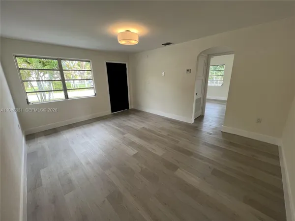 an empty room with wooden floor and windows