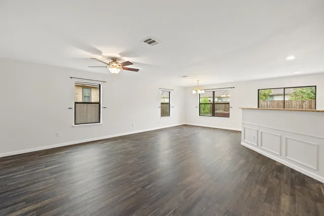 a view of an empty room with a window and wooden floor