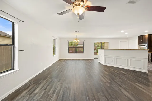 a view of an empty room with window and wooden floor