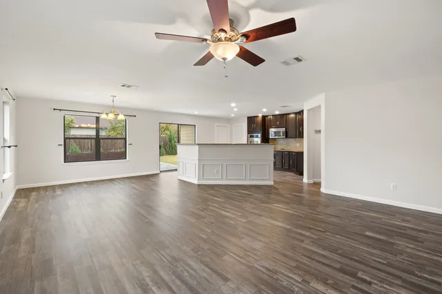 a view of an empty room with window and wooden floor