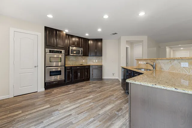 a view of kitchen with stainless steel appliances kitchen island sink refrigerator and cabinets