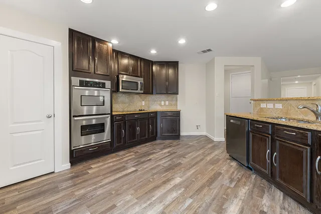 a kitchen with stainless steel appliances granite countertop a sink a stove and a refrigerator