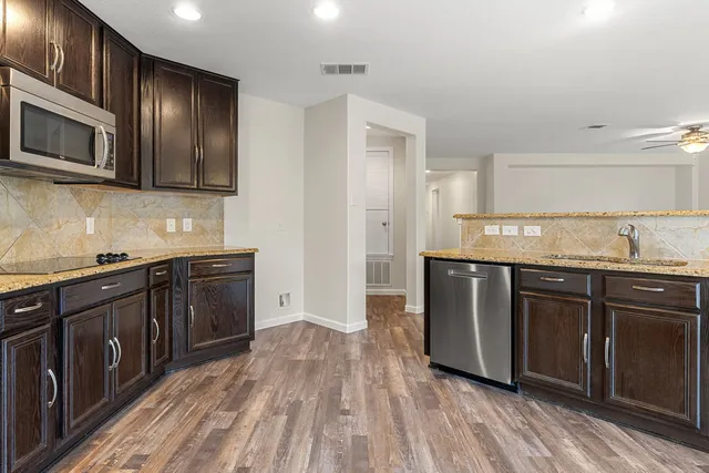 a large kitchen with stainless steel appliances granite countertop a stove top oven and sink