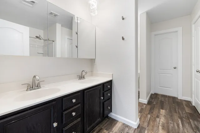 a view of an empty room with wooden floor and a ceiling fan