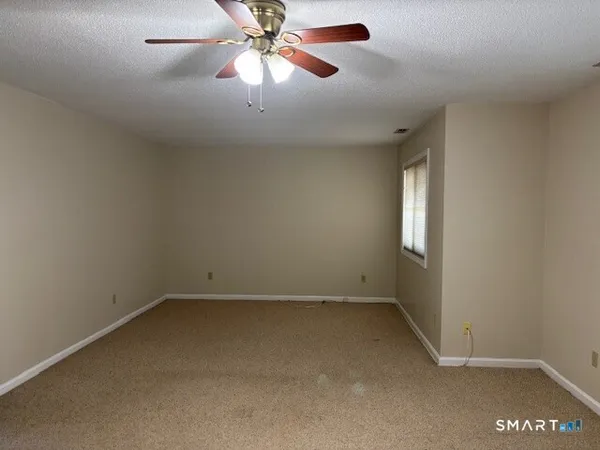 an empty room with a window and a fan