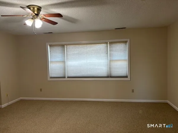 an empty room with a chandelier fan and windows