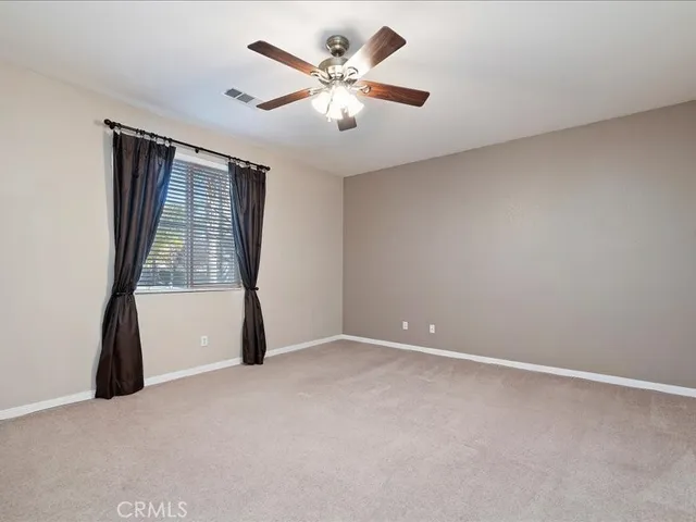 an empty room with a window and a fan
