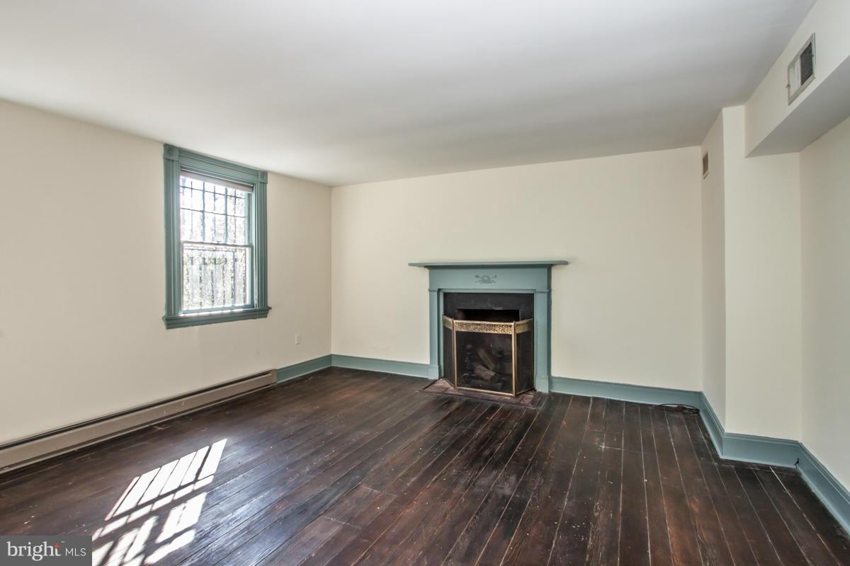 315 Farmhouse Road Accokeek, MD 20607 - Photo 9 of 30 an empty room with wooden floor a fireplace and windows