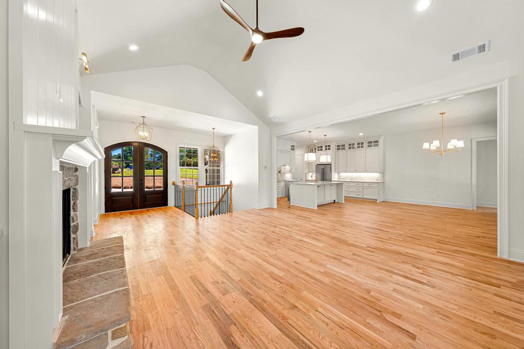 707 Vickery Street Extension Hartwell, GA 30643 - Photo 8 of 50 A spacious, open-concept living area with gleaming hardwood floors, a prominent stone fireplace, and a contemporary kitchen beyond.