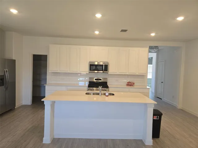 a large kitchen with stainless steel appliances granite countertop a stove a sink and a refrigerator