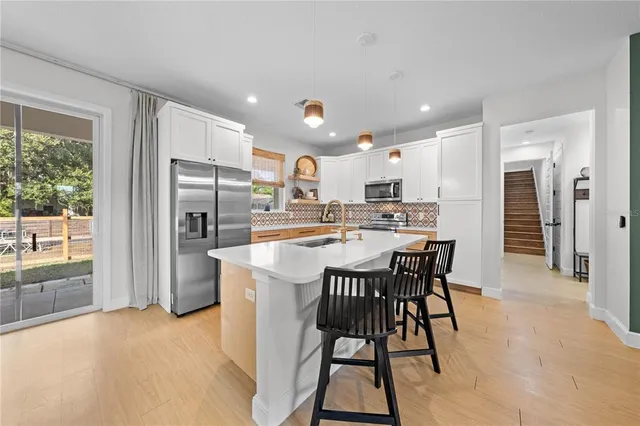 a kitchen with stainless steel appliances kitchen island granite countertop a dining table chairs and refrigerator
