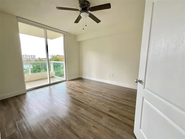 an empty room with wooden floor fan and windows