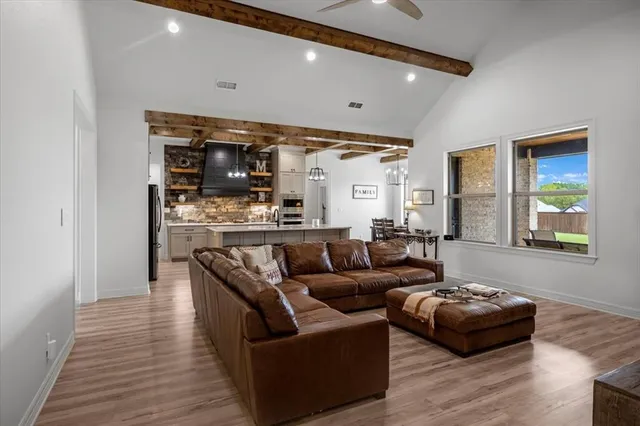 a living room with stainless steel appliances furniture and wooden floor
