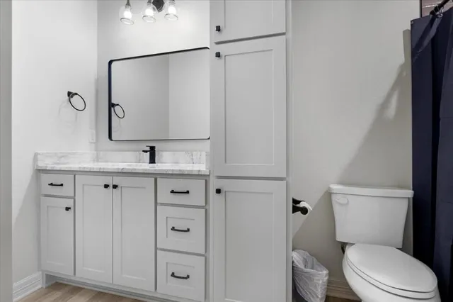 a bathroom with a granite countertop toilet sink and mirror