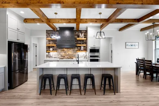 a kitchen with stainless steel appliances granite countertop a table chairs sink and cabinets