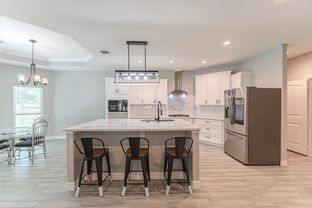 a large kitchen with stainless steel appliances kitchen island a large counter top a sink a stove and a refrigerator