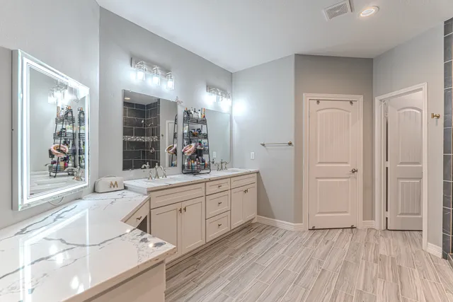 a en suite bathroom with a double vanity sink a mirror and a bathtub