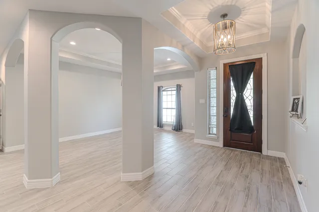 a view of a hallway with wooden floor and chandelier
