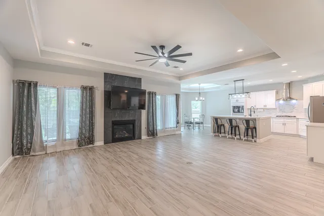 a view of an empty room with kitchen and fireplace