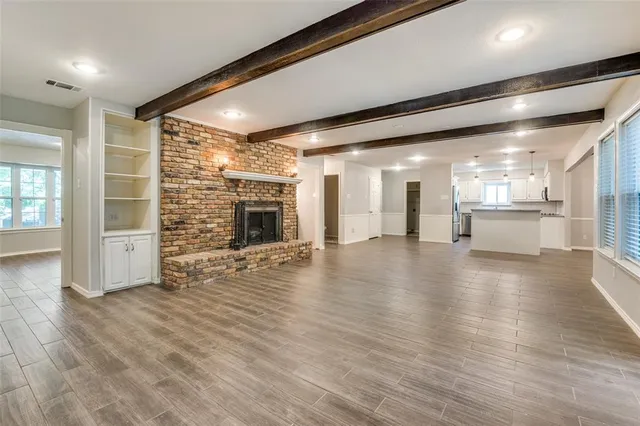 an empty room with wooden floor and a kitchen