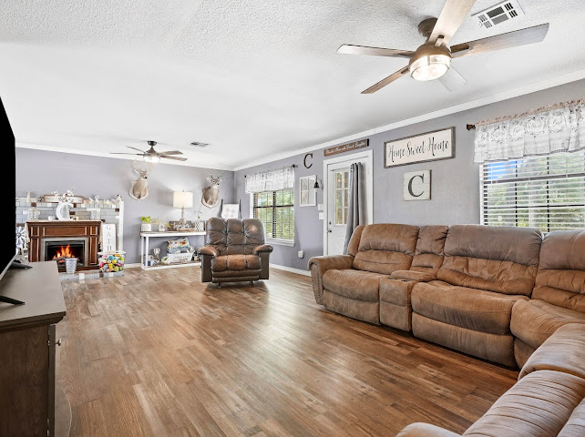 30063 South 4300th Road Stigler, OK 74462 - Photo 16 of 58 Spacious room featuring wood-finish flooring, a fireplace with a tiled surround, and multiple ceiling fans