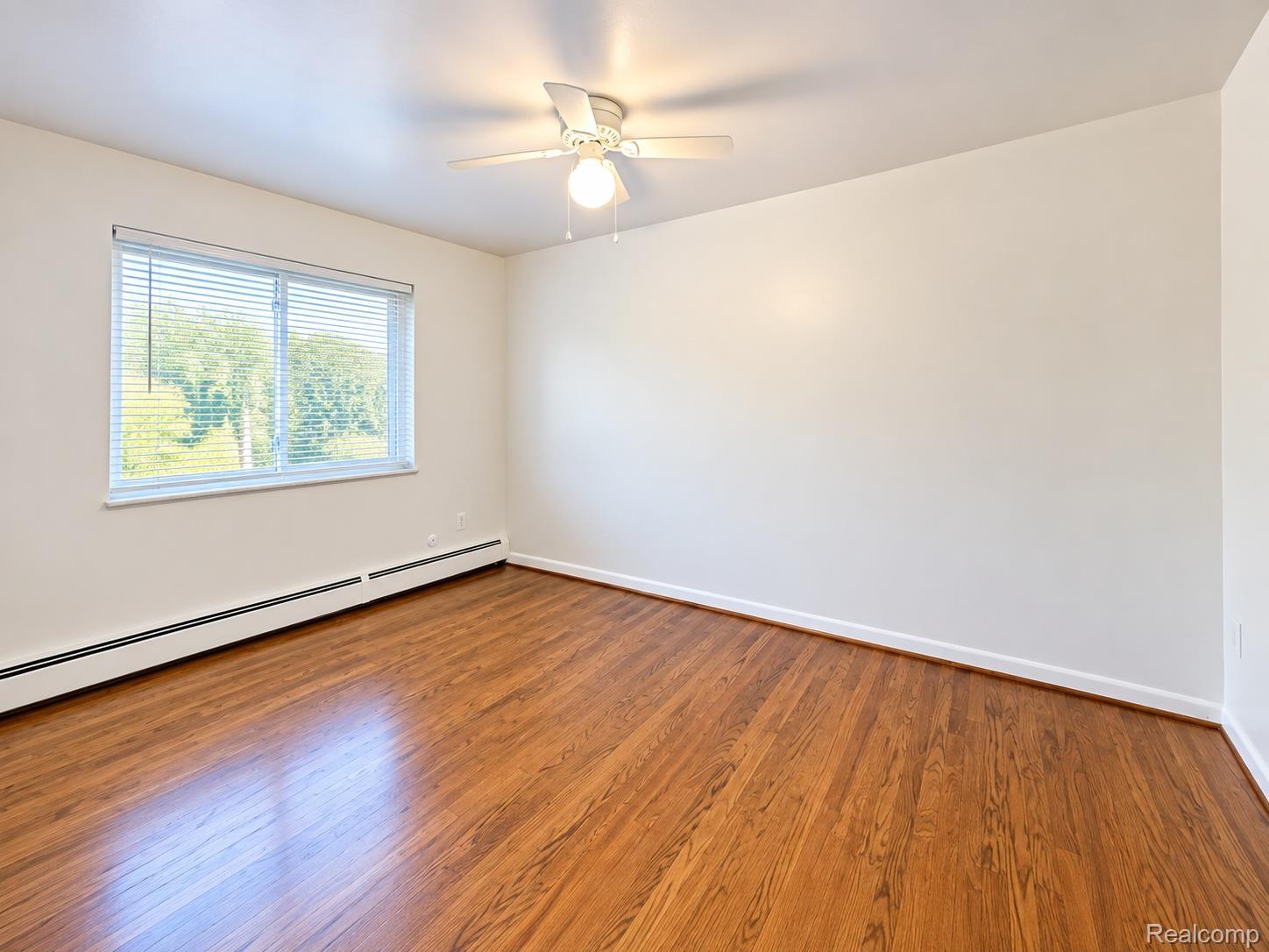475 South Adams Road, Unit 8 Birmingham, MI 48009 - Photo 10 of 15 Hardwood flooring, white walls, and a ceiling fan with integrated lighting