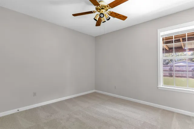 an empty room with windows and chandelier fan