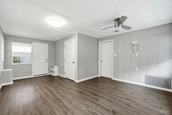 a view of an empty room with window and wooden floor