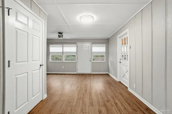 a view of an empty room with a window and wooden floor