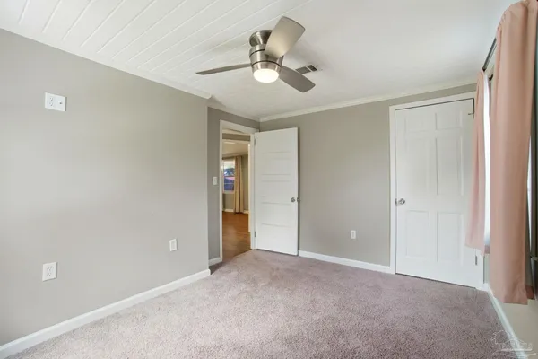 a view of an empty room and chandelier fan