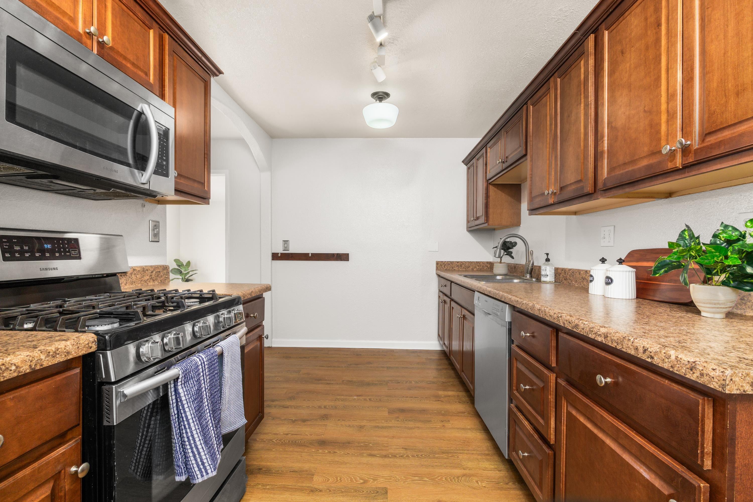 3316 Rucker Road Lompoc, CA 93436 - Photo 9 of 24 a kitchen with stainless steel appliances granite countertop a stove a sink dishwasher and microwave with wooden cabinets