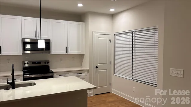 a kitchen with stainless steel appliances a stove a sink and white cabinets